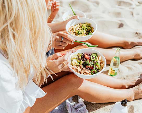 photo of two women on beach eating Tocaya meals