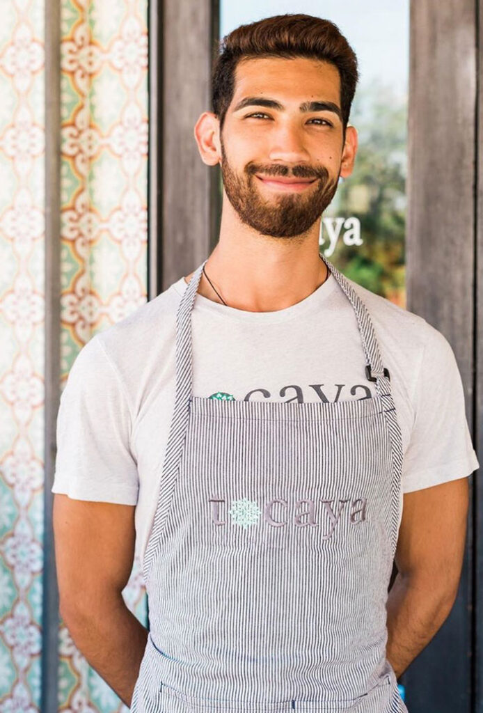 Image of a brown haired Tocaya employee with a beard smiling in a Tocaya t-shirt and a Tocaya apron on top.