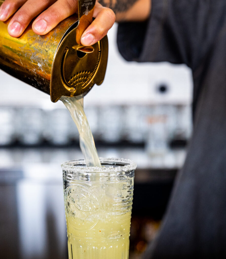 a bartender pouring a cold mixed drink