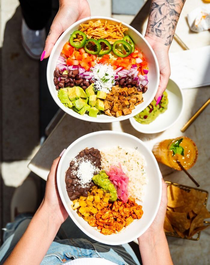 photo of two people's hands holding two different Tocaya meals