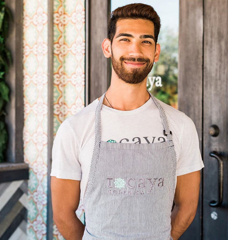 Image of a brown haired Tocaya employee with a beard smiling in a Tocaya t-shirt and a Tocaya apron on top.