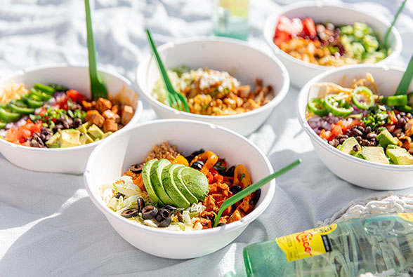 Image of five rice bowls displayed on a white blanket, with a partial view of clear soda in the front right hand corner of the image.